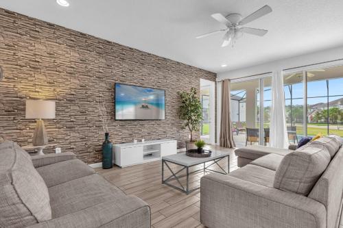uma sala de estar com dois sofás e uma parede de tijolos em Upstay - Sonoma Resort Home w Private Pool em Kissimmee