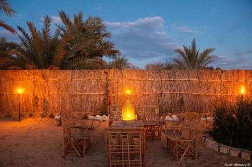 a patio with chairs and a table and a fence at غزاله كامب in Siwa