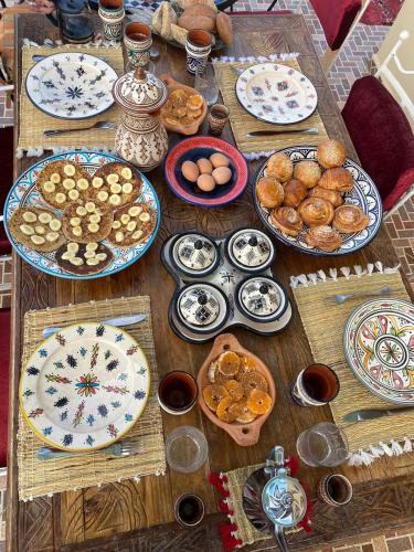 a wooden table with plates of food on it at Adrenalin Surf House in Tamraght Ouzdar