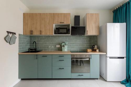 a kitchen with blue cabinets and a white refrigerator at Современные Апартаменты с 2 комнатами 