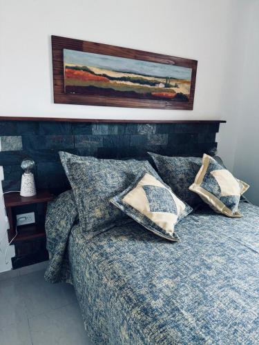a bed with pillows and a painting on the wall at Departamento BELGRANO CENTRO in Paraná