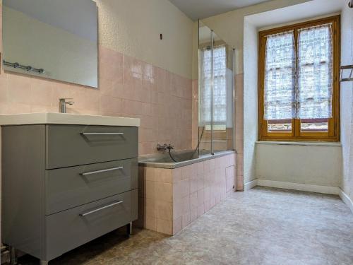 uma casa de banho com um lavatório, uma banheira e um espelho. em Gîte Saint-Didier-sur-Doulon, 5 pièces, 8 personnes - FR-1-582-222 em Saint-Didier-sur-Doulon