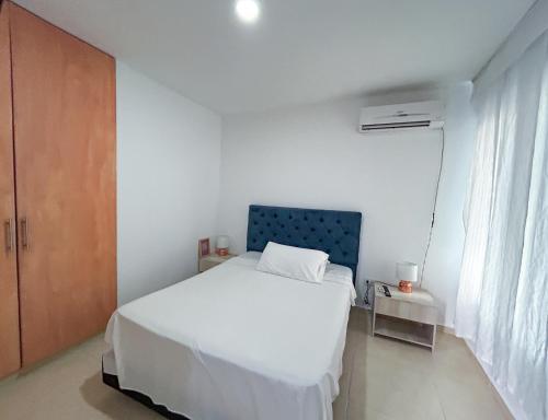 a bedroom with a white bed and a blue headboard at HOTEL EBENEZER in Villavicencio