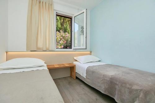 two beds in a room with a window at Apartments by the sea Sobra, Mljet - 22343 in Babino Polje