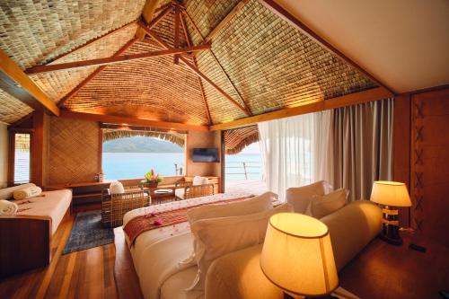 a room with a bed and a couch and a table at Le Taha'a by Pearl Resorts in Motu Tautau