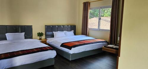 a bedroom with two beds and a window at Yula Hotel Thatluang in Vientiane