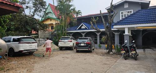 a man washing two cars in a driveway in front of a house at Yula Hotel Thatluang in Vientiane