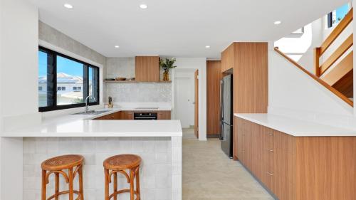 a kitchen with white countertops and wooden stools at Nina's Place in Sawtell