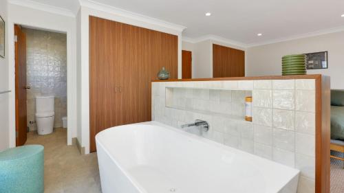 a bathroom with a white tub and a toilet at Nina's Place in Sawtell