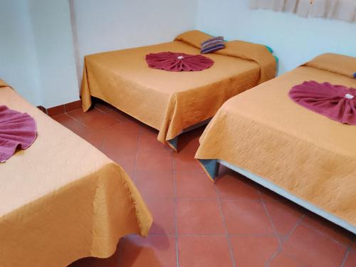 a room with three beds with brown covers on them at Hostal Dulces Sueños in Panajachel