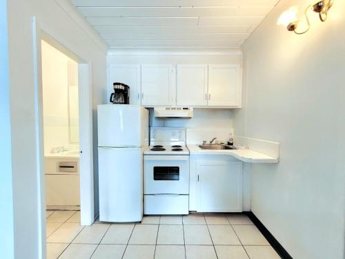 a white kitchen with a white refrigerator and a sink at The Villager Inn Princeton Motel in Princeton