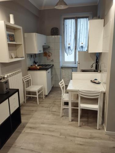 una piccola cucina con tavolo e sedie bianchi di Zena Est a Genova
