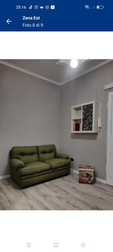 un soggiorno con divano verde in una camera di Zena Est a Genova
