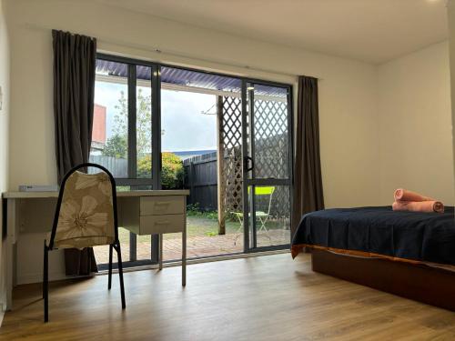 um quarto com uma cama, uma secretária e uma janela em New Lynn Tidy House em Auckland