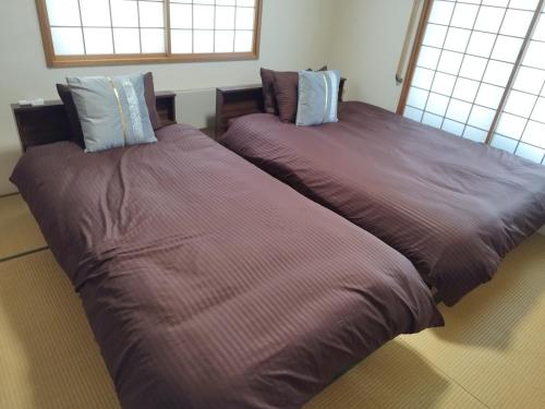 two beds sitting next to each other in a room at Guest House Nishimiyanosawa in Teine