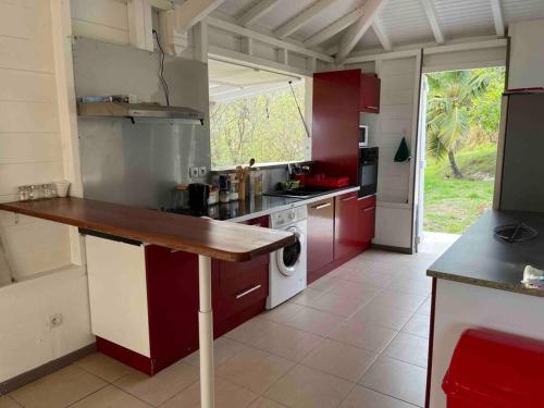 une cuisine avec des placards rouges et blancs et un comptoir dans l'établissement Carbet Beaujolais, au Vauclin