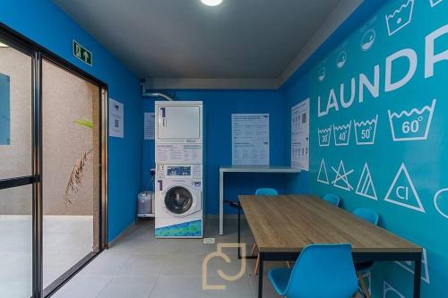 een blauwe kamer met een tafel en een wasmachine bij Loft 406 in Curitiba