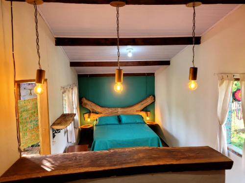 デルフィノポリスにあるPousada Fazenda São Pedroの木の木がある部屋に緑のベッドが備わるベッドルーム1室が備わります。