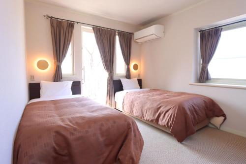 a bedroom with two beds and a window at Pension Angelica in Minami Aso