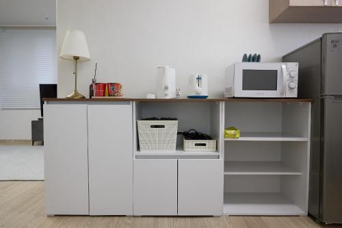 a white cabinet with a microwave and a refrigerator at Ogeum stay in Seoul