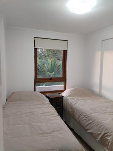 1 dormitorio con 2 camas y ventana en Departamento con exelente ubicacion, en Pucón