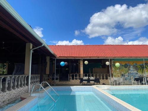 einen Pool in einem Resort mit rotem Dach in der Unterkunft Hotel y restaurante Tabaconess in Guácimo