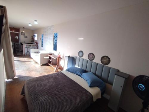 a bedroom with a bed with blue pillows and a kitchen at Recanto das Pedras - Loft Container in São Thomé das Letras