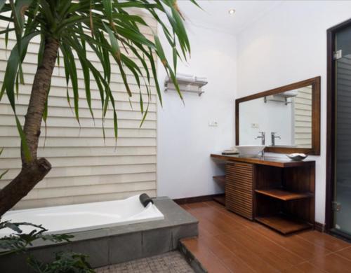 a bathroom with a tub and a sink and a palm tree at Villa Cantik Tresna in Seminyak