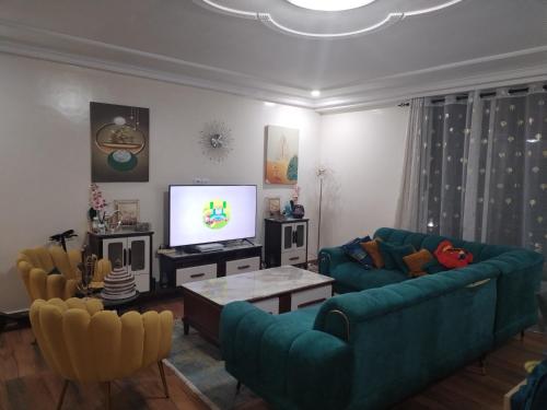 een woonkamer met twee blauwe banken en een tv bij Appartement Elegant in Conakry