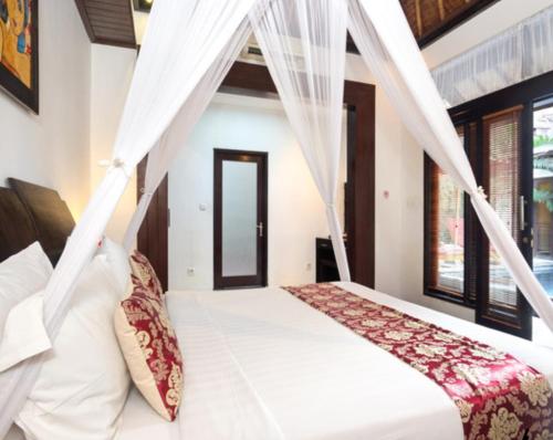 a bedroom with a bed with a mosquito net at Villa Cantik Tresna in Seminyak
