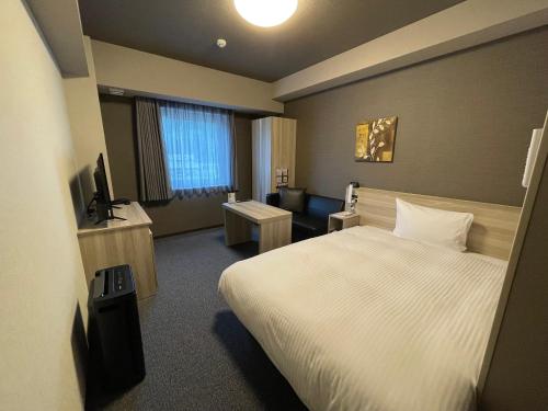 ein Hotelzimmer mit einem Bett und einem TV in der Unterkunft Hotel Route Inn Ohi Takahama in Takahama