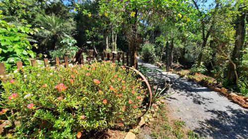a garden with flowers and a wooden fence at NOMADAS chales, mini casinhas, bangalôs e area de camping in Bonito