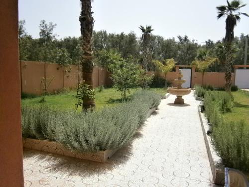 a garden with a fountain and palm trees at Villa isouktan in Sbiti
