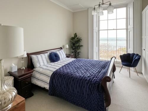 a bedroom with a bed with a blue comforter and a window at Admirals Lookout in Ilfracombe