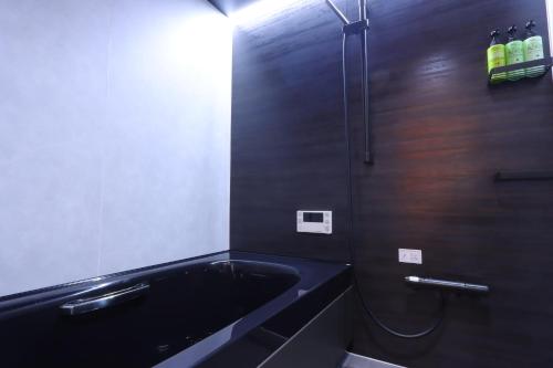 a bathroom with a black tub and a shower at Pension Angelica in Minami Aso