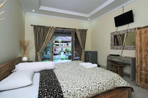 a bedroom with a bed and a desk and a television at Bale Bali Inn in Ubud