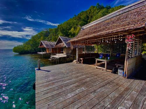 a wooden dock with a house on the water at Avinsea Homestay in Besir