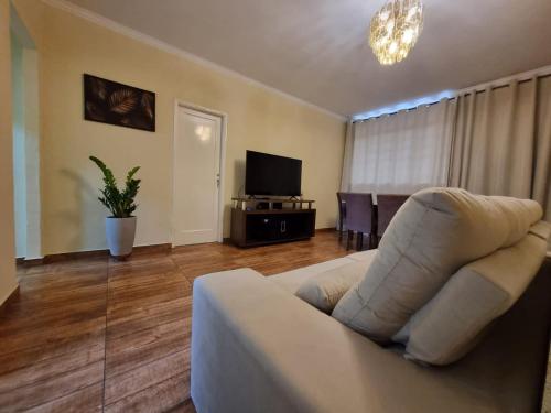 un soggiorno con divano bianco e TV di Apart Roma l Amplo e confortável no Centro de Águas de Lindóia ad Águas de Lindóia
