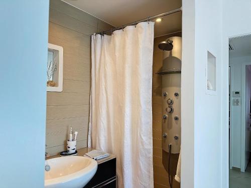 La salle de bains est pourvue d'un rideau de douche blanc et d'un lavabo. dans l'établissement Appartement climatisé avec terrasse et parking, face à la mer - FR-1-715-76, à Mauguio