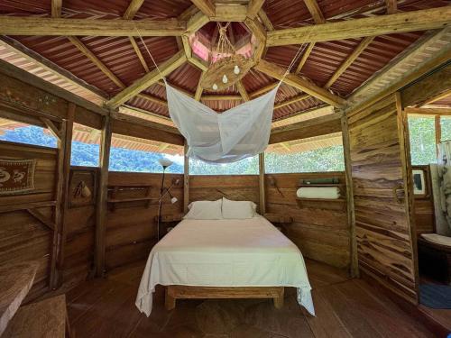 a bedroom with a bed in a wooden cabin at Cinduli Finca Orgánica Cacaotera in Guachaca