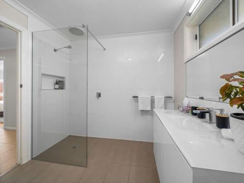 a white bathroom with a shower and a sink at Nook on Nixon in Shepparton