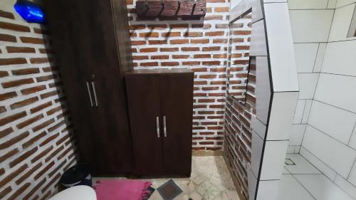 a bathroom with a brown cabinet in a brick wall at NOMADAS chales, mini casinhas, bangalôs e area de camping in Bonito