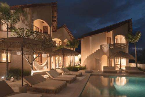 a villa with a swimming pool with chairs and umbrellas at Dune Seseh in Munggu