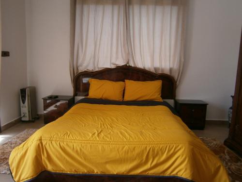 a bedroom with a large bed with a yellow blanket at Villa isouktan in Sbiti