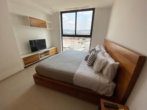 a bedroom with a bed and a large window at Departamento 1 habitación - Latitud La Victoria a 5 minutos del centro in Querétaro