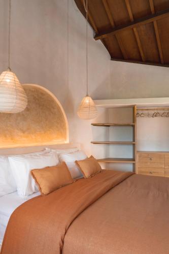 a bedroom with a large bed with two lights at Dune Seseh in Munggu