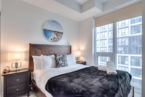 a bedroom with a large bed and two windows at RivetStays - The Jarvis in Toronto