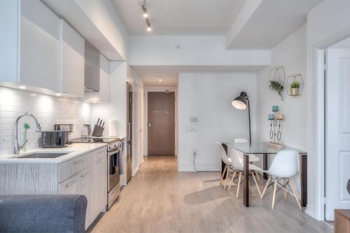 a kitchen with white cabinets and a table and chairs at RivetStays - The Jarvis in Toronto