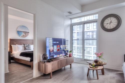 a bedroom with a large tv and a bed and a clock at RivetStays - The Jarvis in Toronto