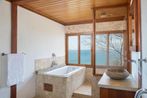 ein Bad mit einer Badewanne und einem großen Fenster in der Unterkunft Casa Amico Beach House in El Gigante